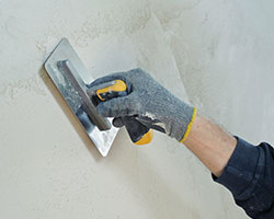 A plasterer skimming a plastered wall